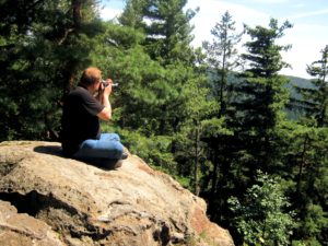 Freelancer photographer sitting on a rock in a forest